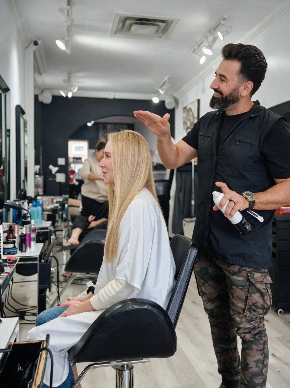 Pezh smiling while finishing a client's long blonde hair